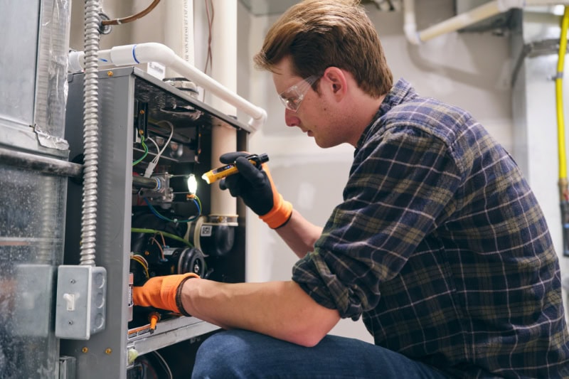 A service tech in front of HVAC unit.