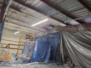 Image of spray foam insulation being applied in a warehouse.